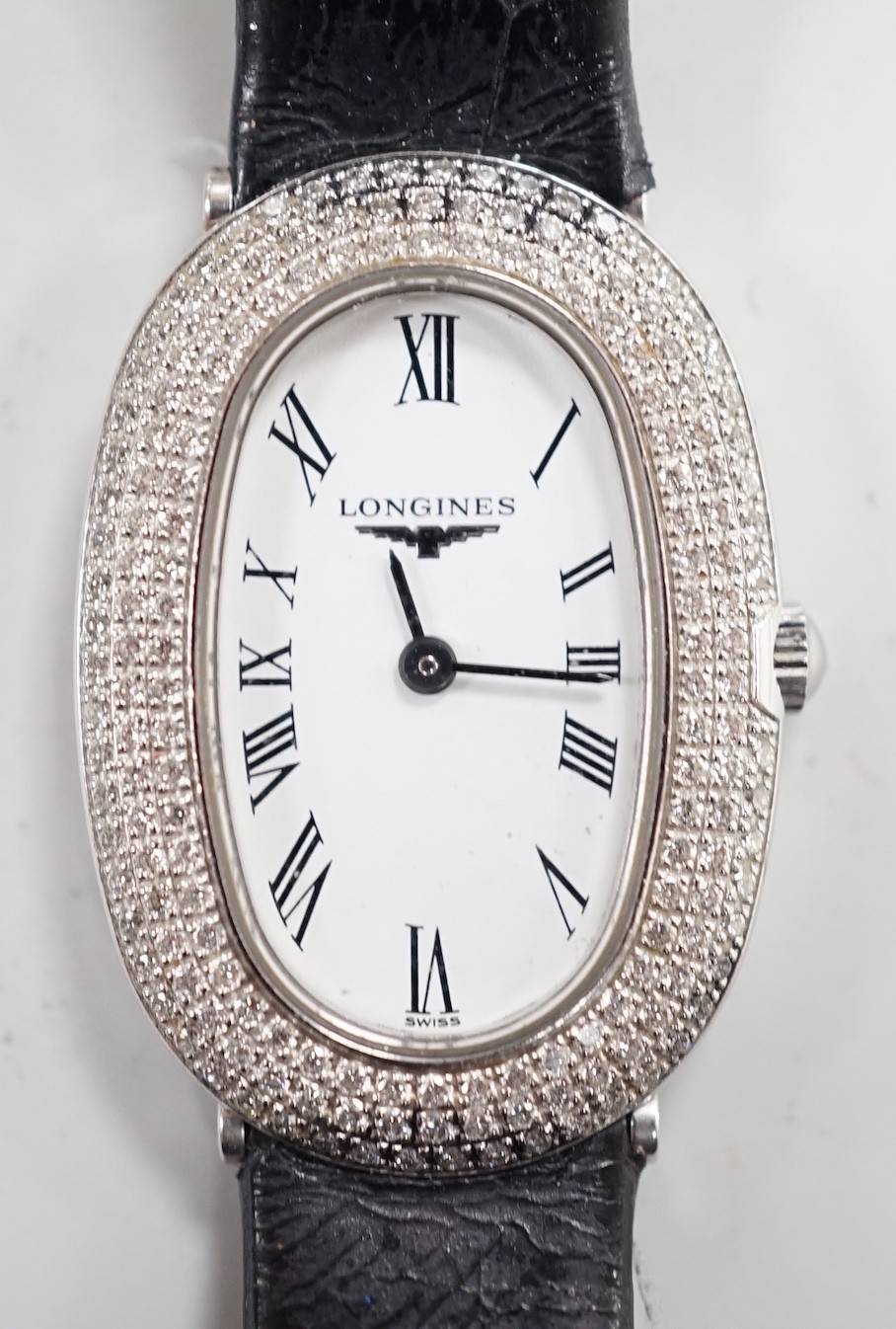 A lady's 2010 18ct white gold and diamond set Longines oval quartz wrist watch, with Roman dial, case back numbered 32157237, on Longines leather strap, with stainless steel buckle, case diameter 21mm, the total diamond